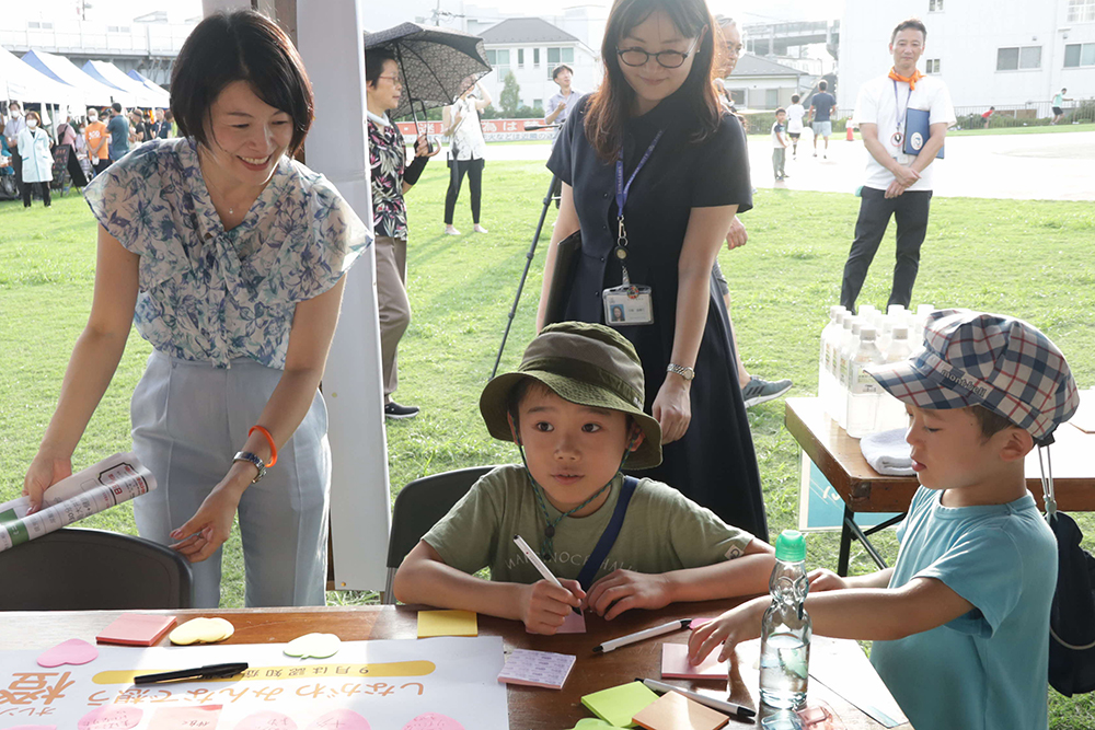 寄せ書きコーナーで子どもと話す森澤区長の画像